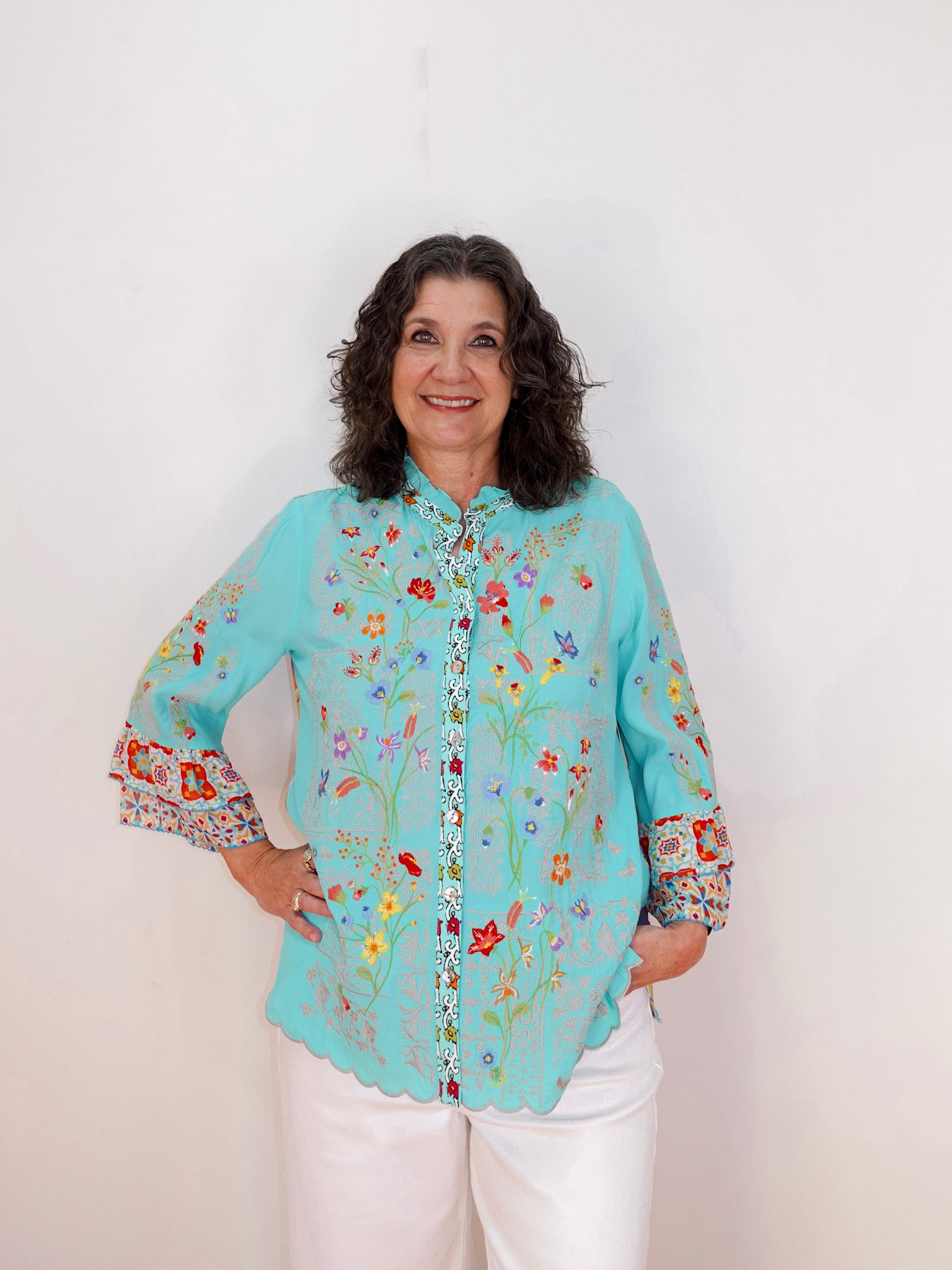 Woman wearing a light blue floral embroidered blouse against a white background