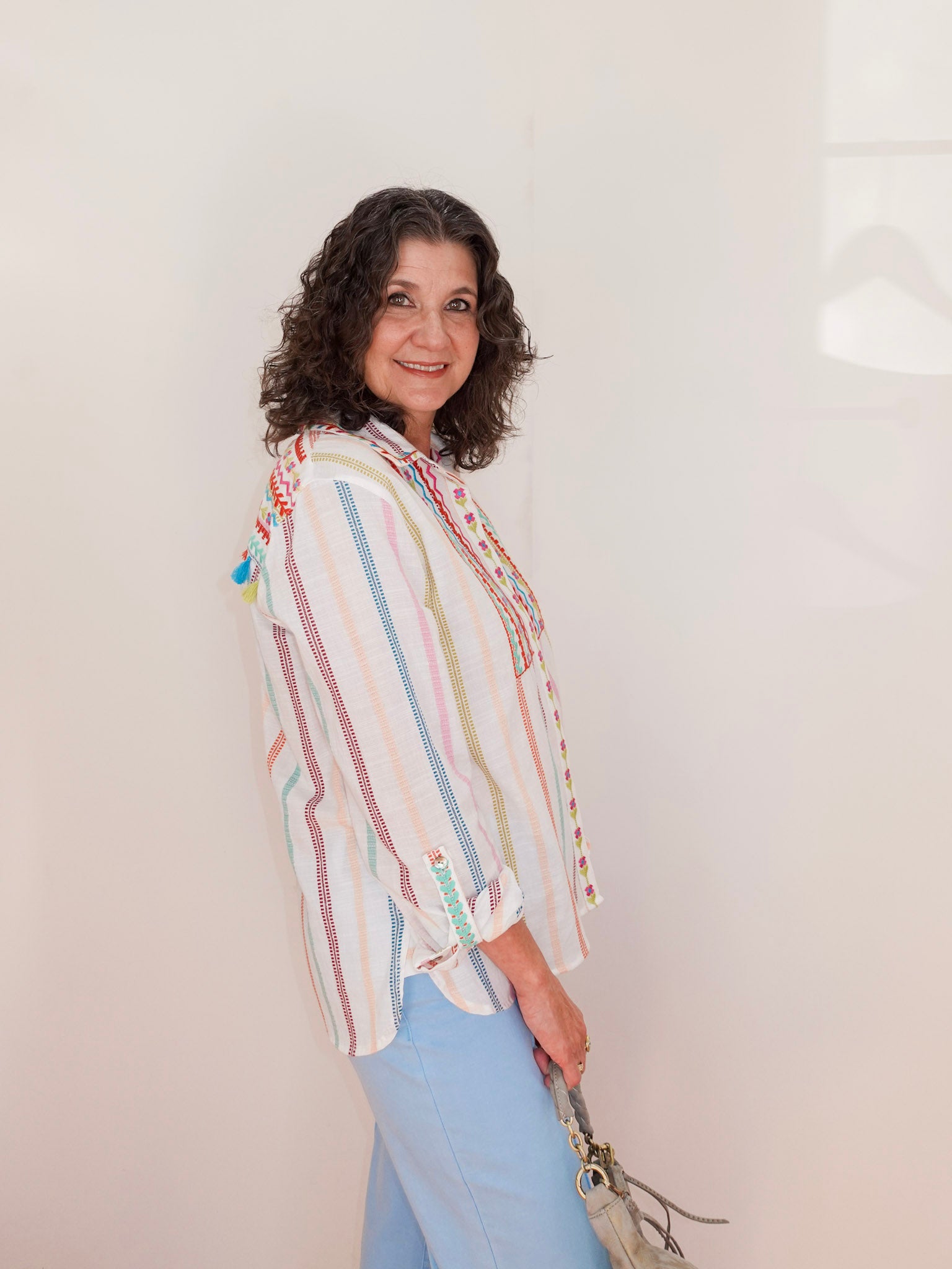 Woman wearing a colorful striped shirt against a plain background