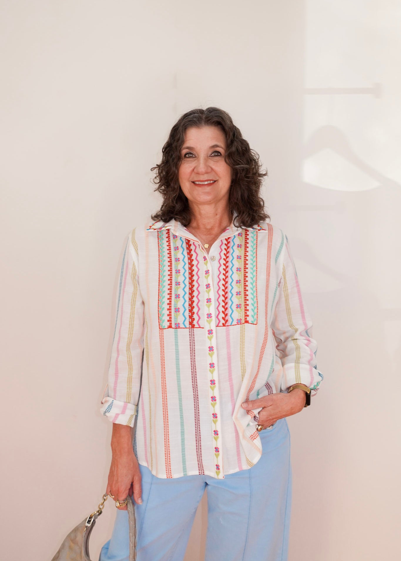 Woman wearing a colorful striped shirt with a geometric pattern on a plain background