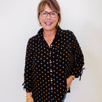 Woman wearing a black polka dot shirt against a white background