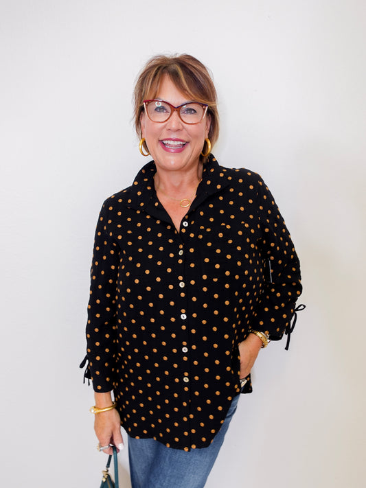 Woman wearing a black polka dot shirt against a white background