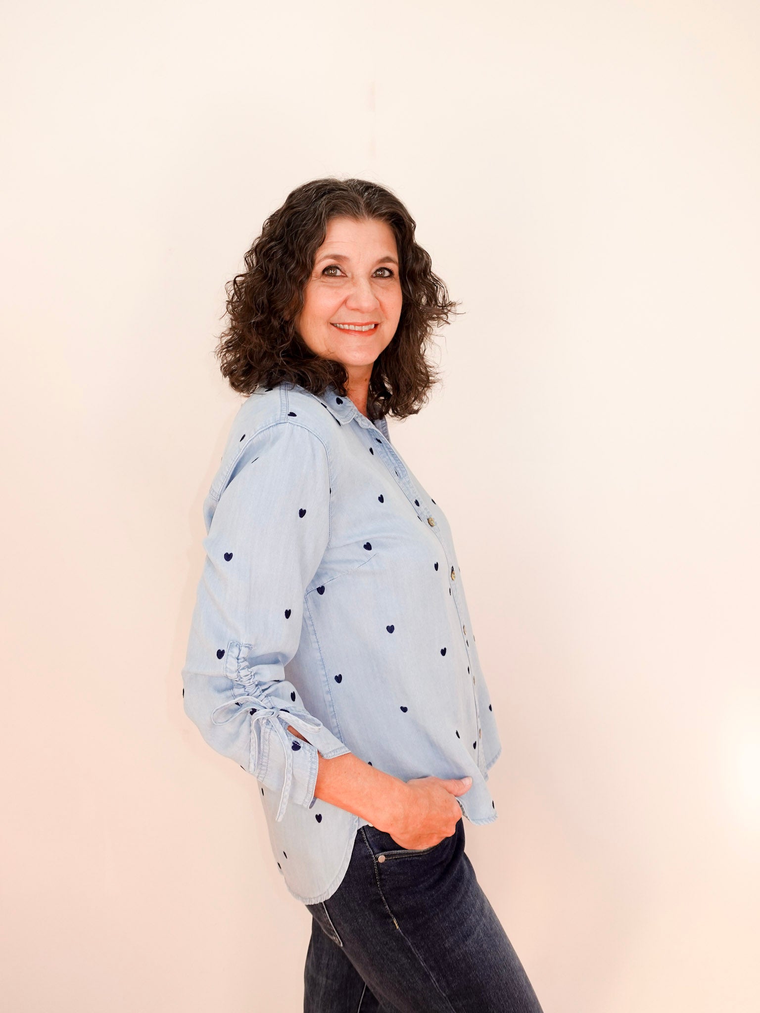 Woman wearing a light blue shirt with black polka dots against a beige background