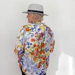 Person wearing a colorful floral shirt and a hat against a white background