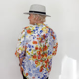 Person wearing a colorful floral shirt and a hat against a white background
