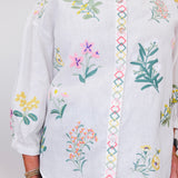 White blouse with colorful floral embroidery on a plain background