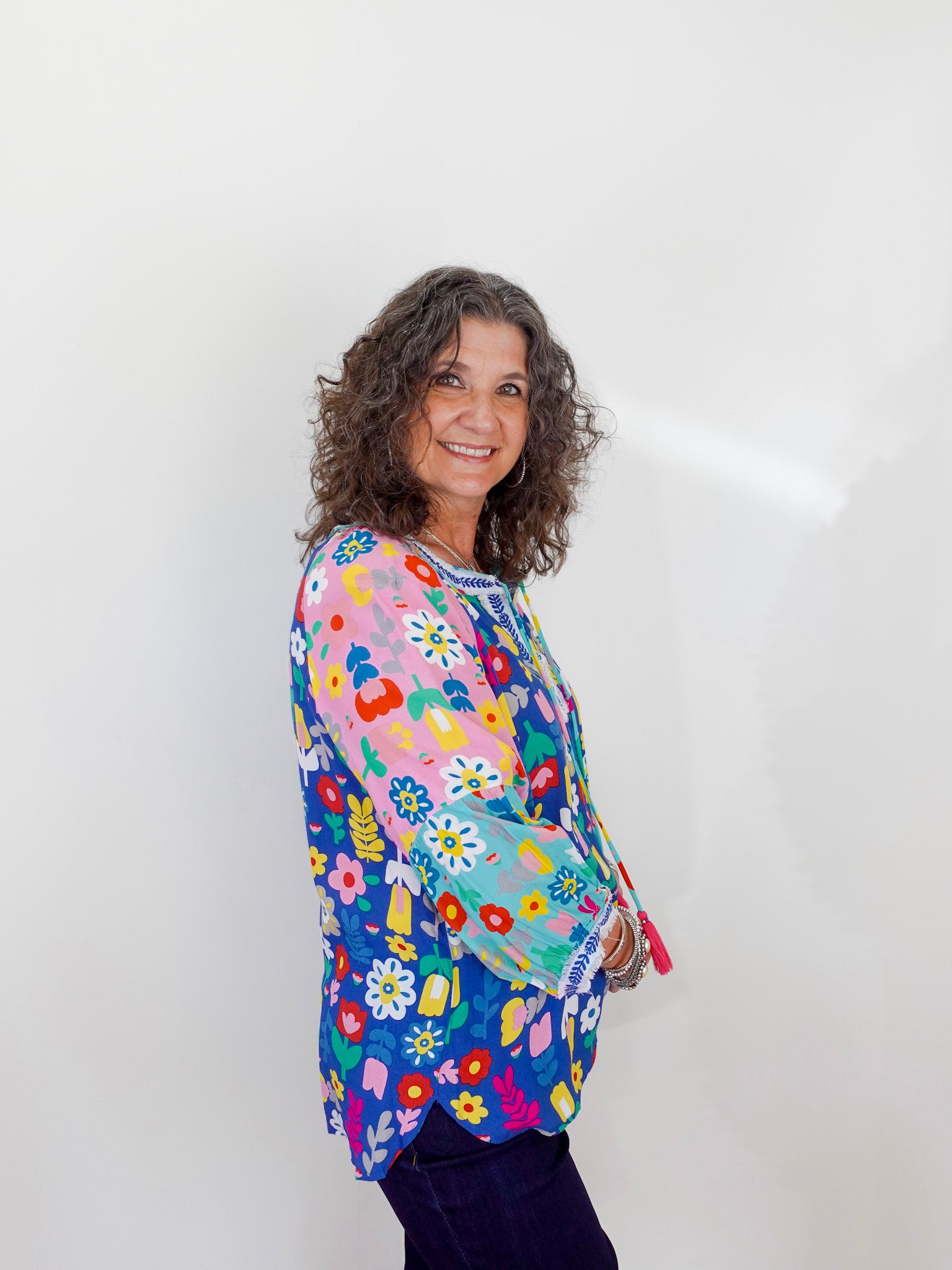 Woman wearing a colorful floral-patterned shirt against a white background