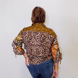 Person wearing a patterned shirt with leopard print and other designs against a white wall.
