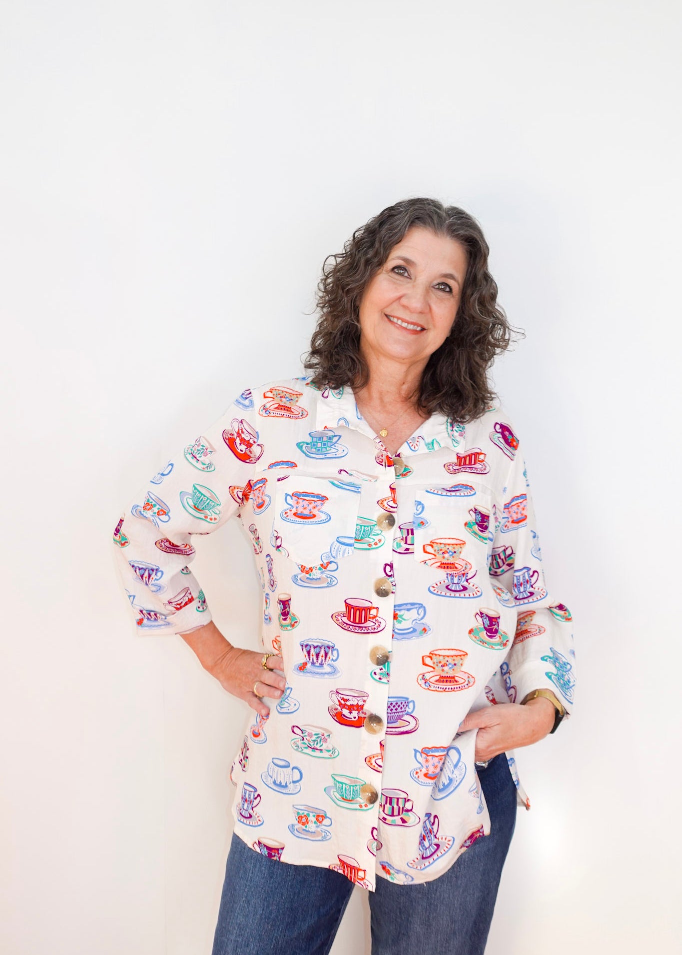 Woman wearing a colorful shirt with tea cup pattern against a white background