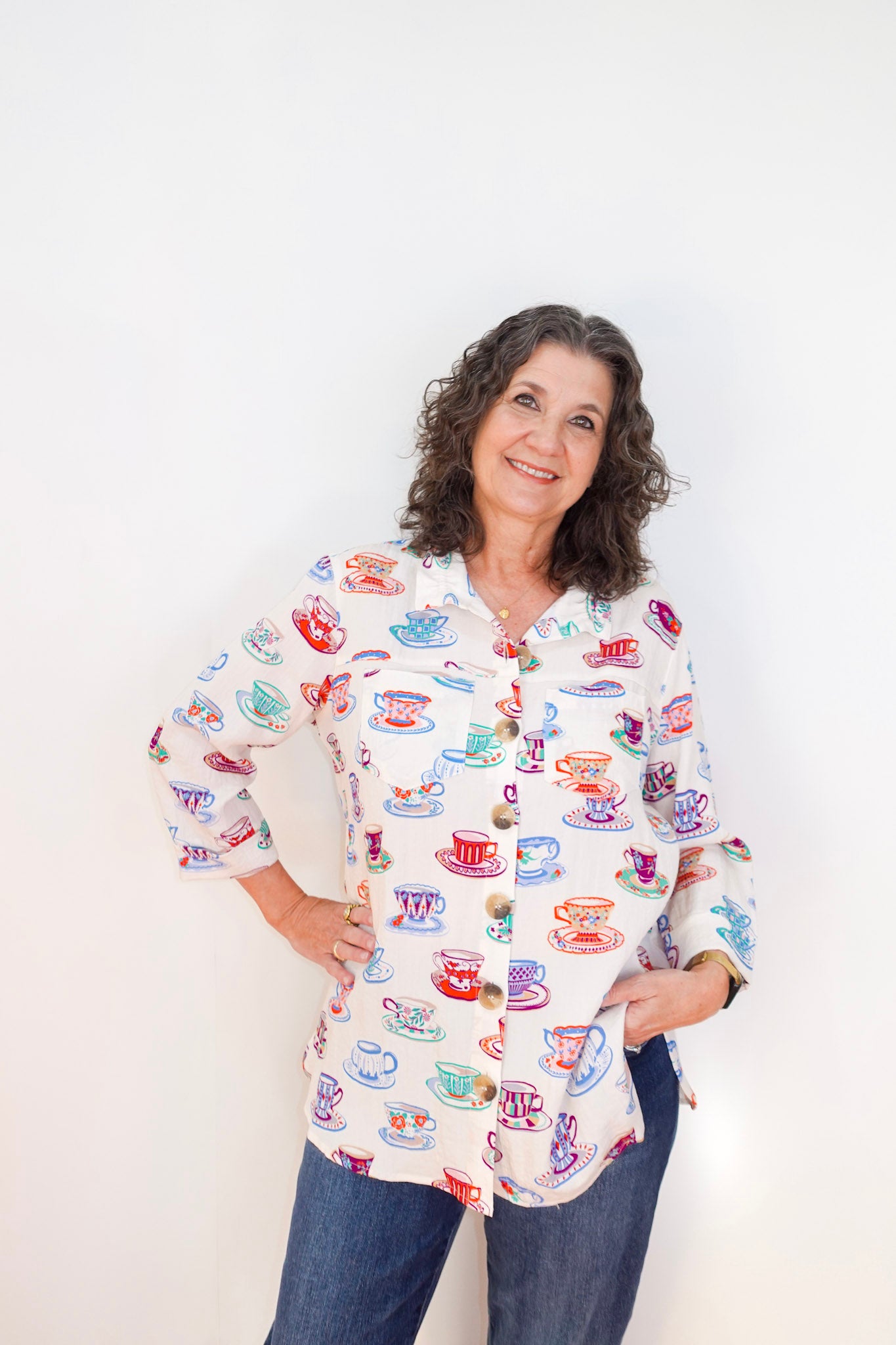Woman wearing a colorful shirt with tea cup pattern against a white background
