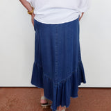 Person wearing a white top and blue denim skirt on a plain background