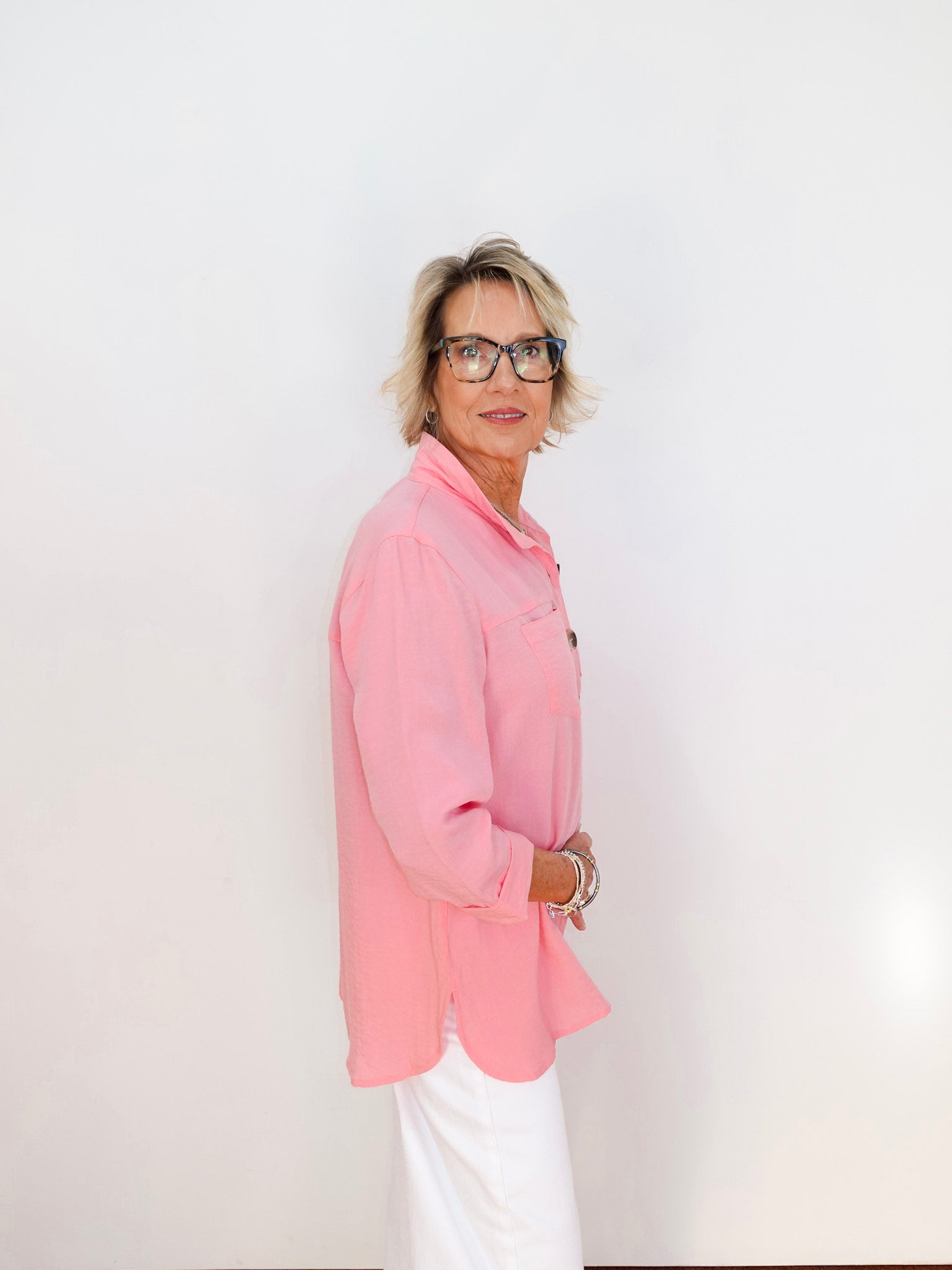 Person wearing a pink shirt and white pants against a plain background