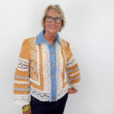 Woman wearing a patterned jacket over a blue shirt against a white background