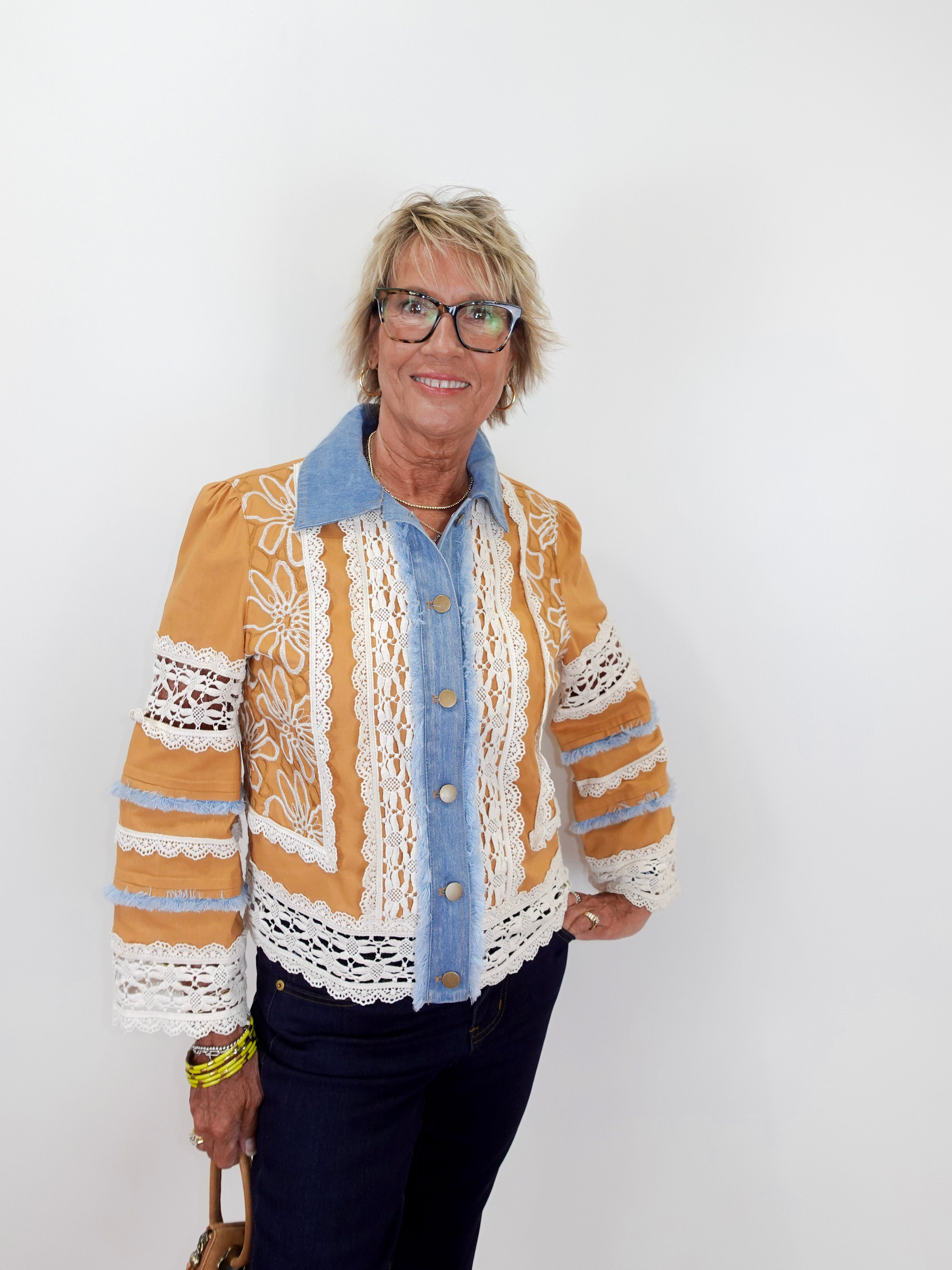 Woman wearing a patterned jacket over a blue shirt against a white background