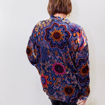 Person wearing a colorful patterned shirt against a white background