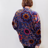 Person wearing a colorful patterned shirt against a white background
