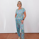 Person wearing a blue floral outfit standing against a white wall.