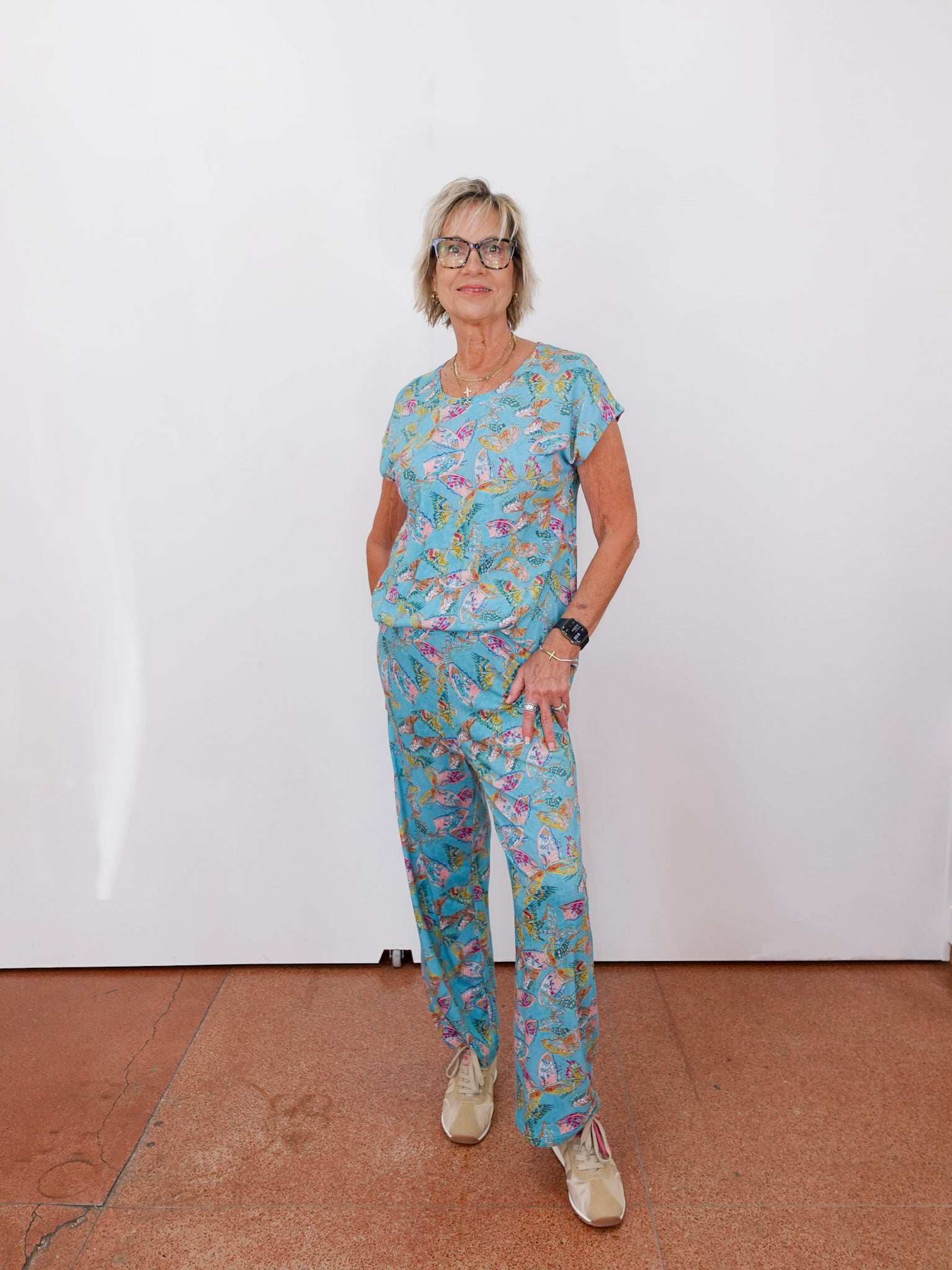 Person wearing a blue floral outfit standing against a white wall.
