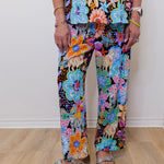 Person wearing colorful floral pants on a wooden floor.