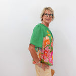 Woman wearing a green blouse with floral patterns on a white background