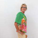 Woman wearing a green blouse with floral patterns on a white background