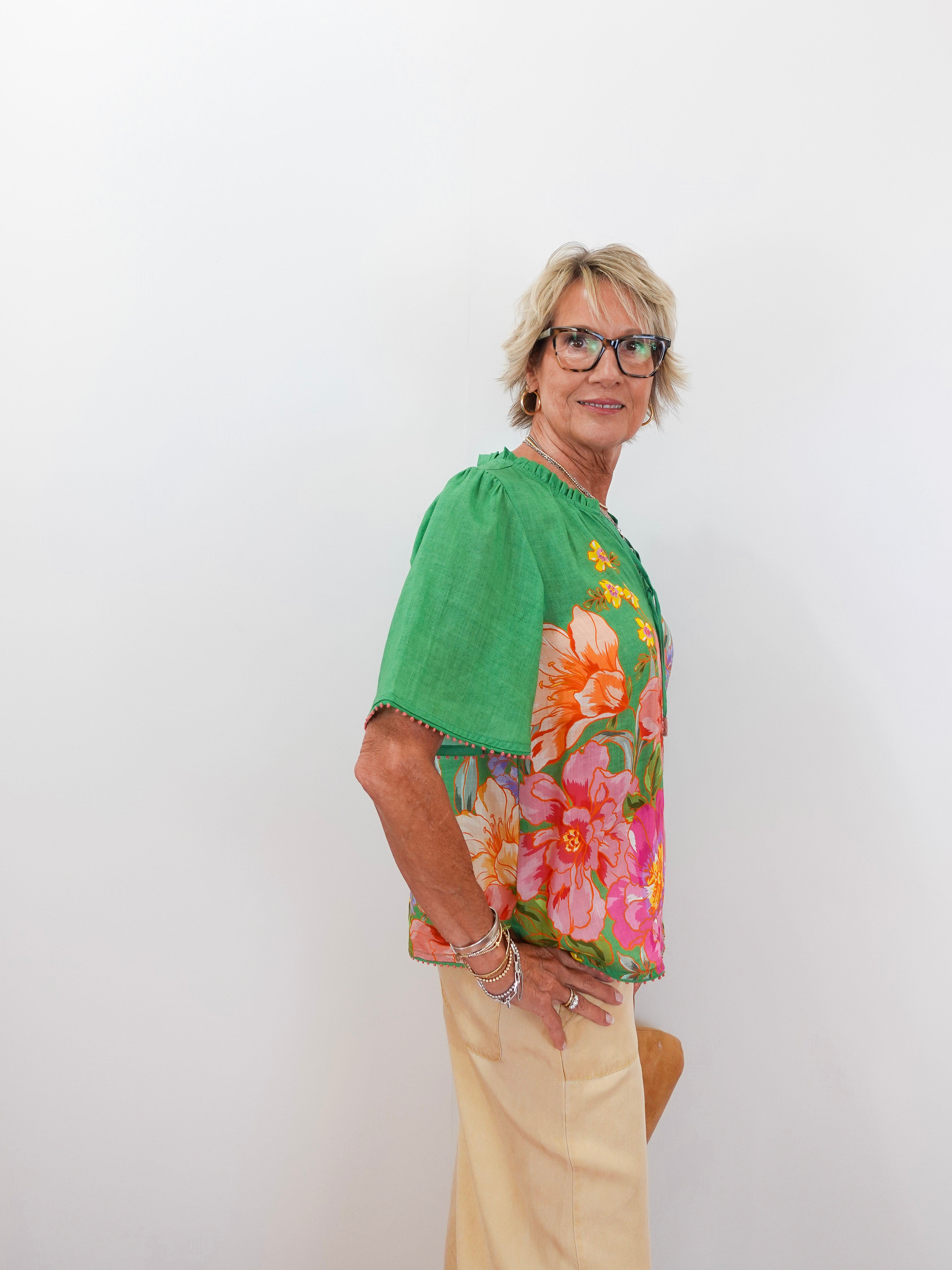 Woman wearing a green blouse with floral patterns on a white background