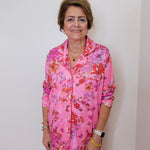 Woman wearing a pink floral outfit against a plain background
