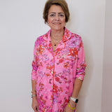 Woman wearing a pink floral outfit against a plain background