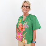 Woman wearing a green floral blouse against a white background