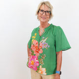 Woman wearing a green floral blouse against a white background