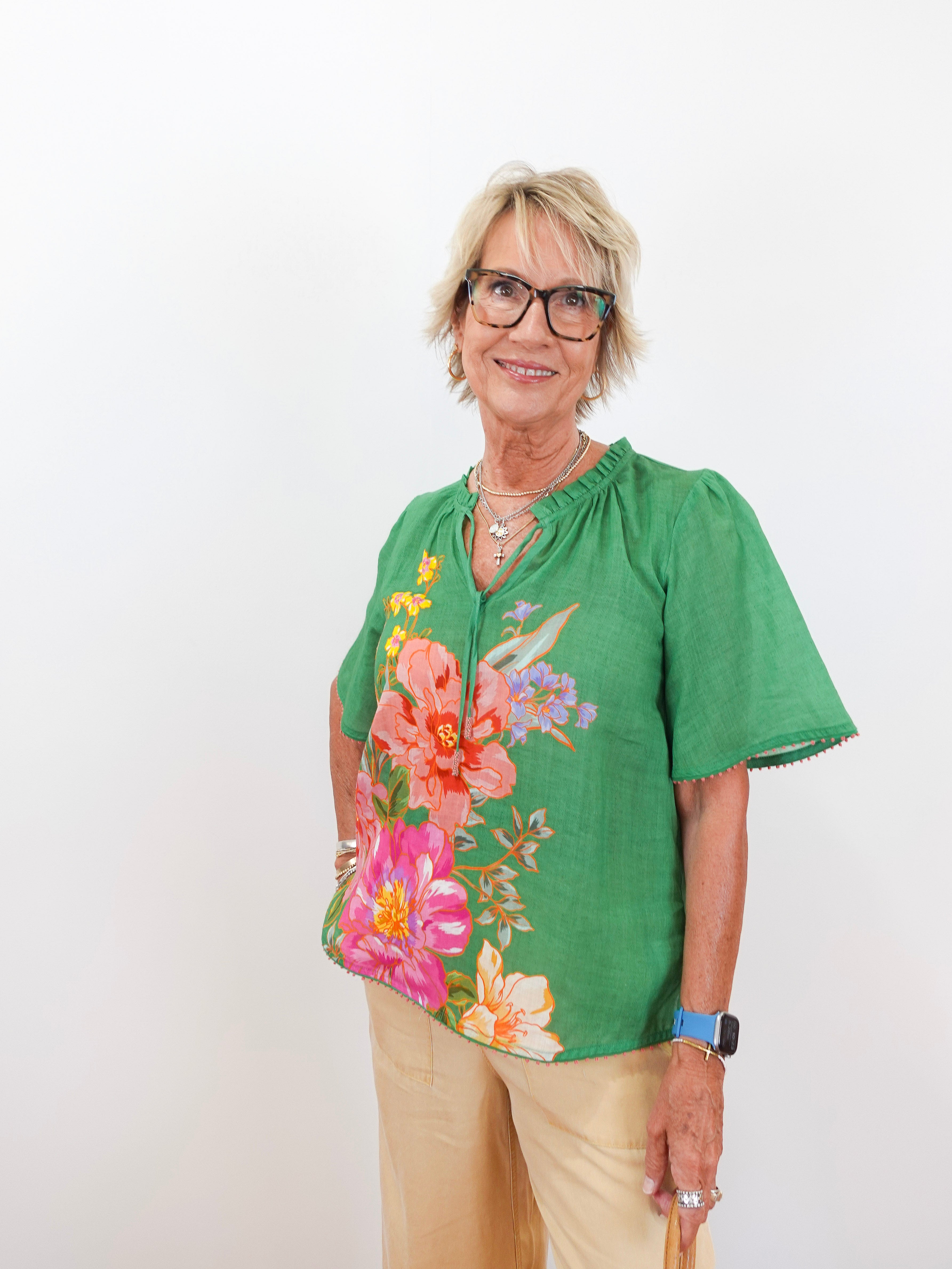Woman wearing a green floral blouse against a white background