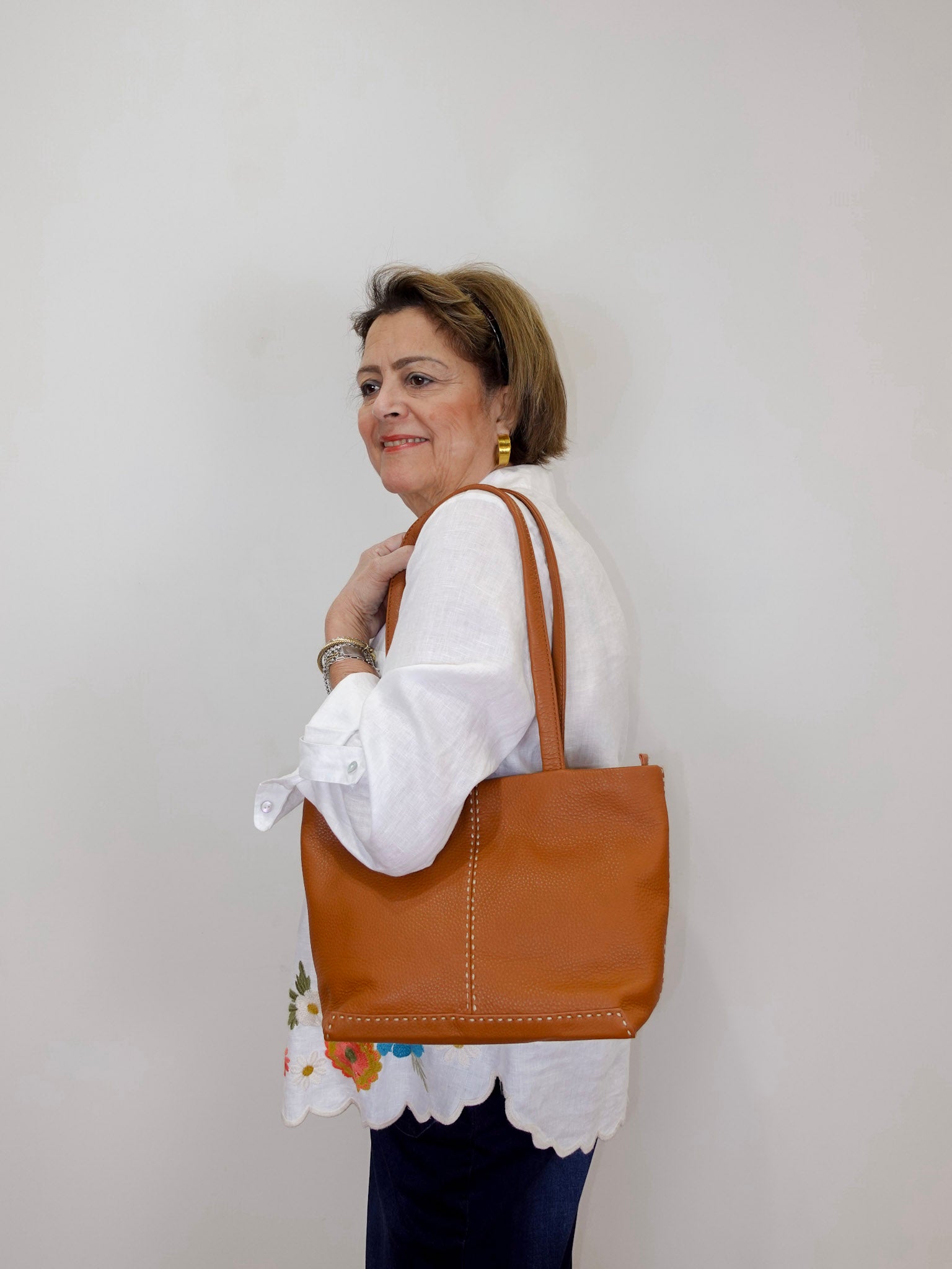 Woman modeling a Johnny Was Frances relaxed linen shirt featuring lightweight white linen, button-front styling, and colorful floral embroidery.