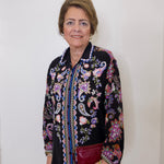 Woman wearing a black floral embroidered jacket against a white background