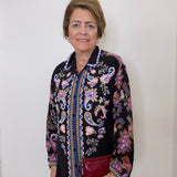 Woman wearing a black floral embroidered jacket against a white background