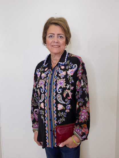 Woman wearing a black floral embroidered jacket against a white background