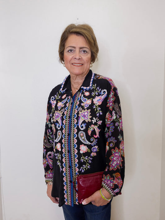 Woman wearing a black floral embroidered jacket against a white background
