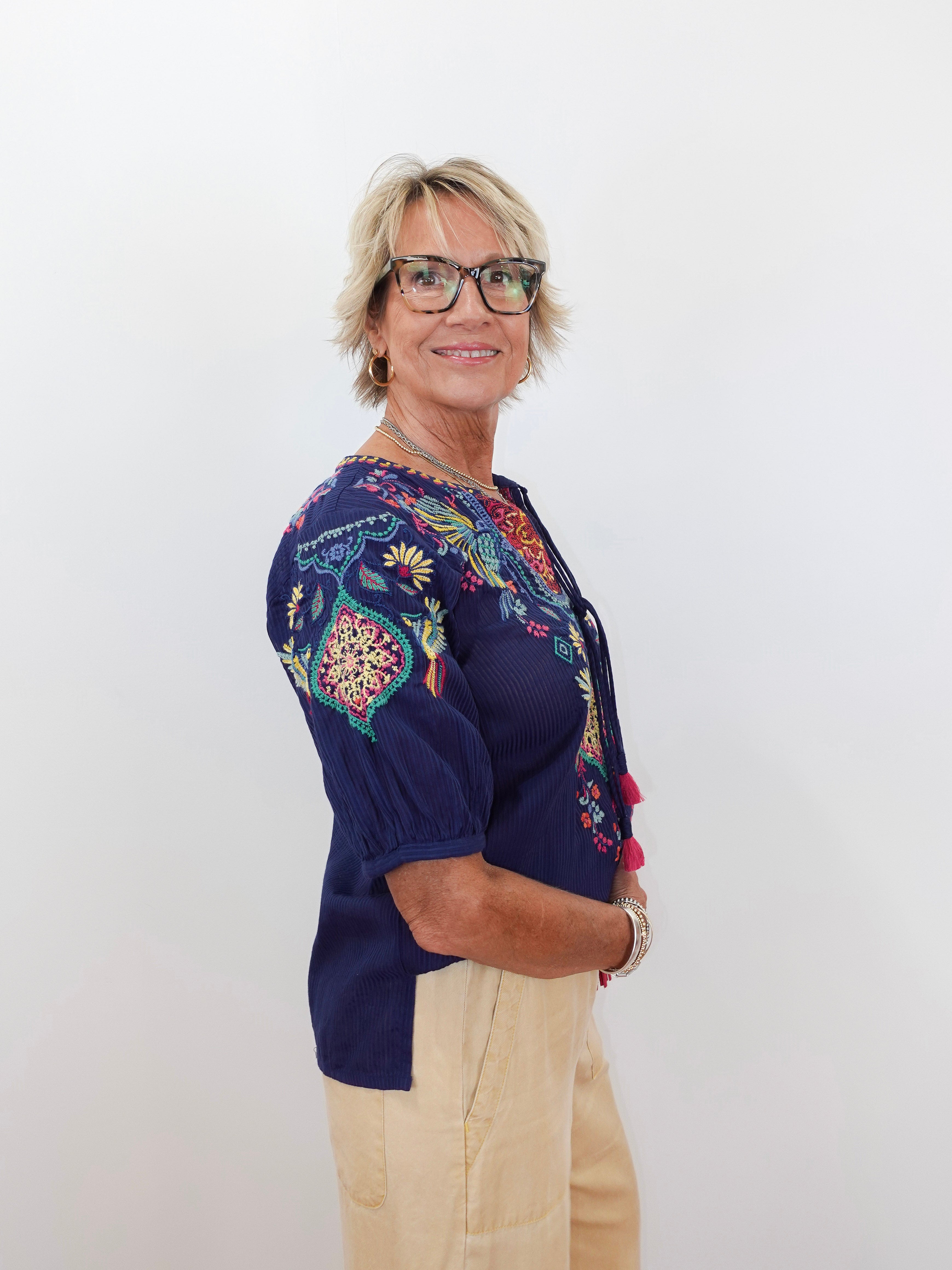 Woman wearing a colorful embroidered top against a white background