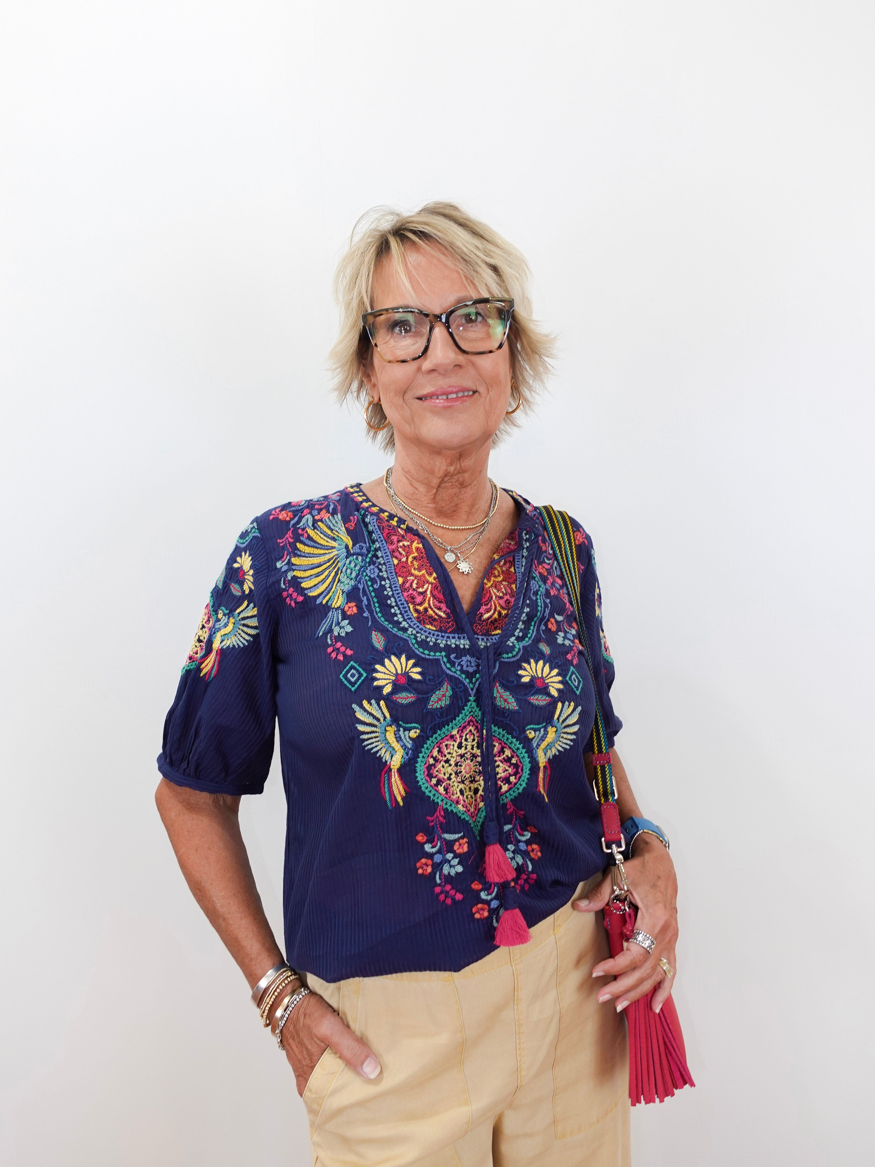 Woman wearing a colorful embroidered blouse with a plain background