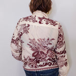 Person wearing a white blouse with red floral patterns against a plain background