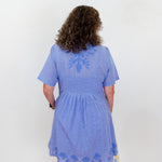 Person wearing a blue dress with lace details on a white background