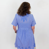 Person wearing a blue dress with lace details on a white background