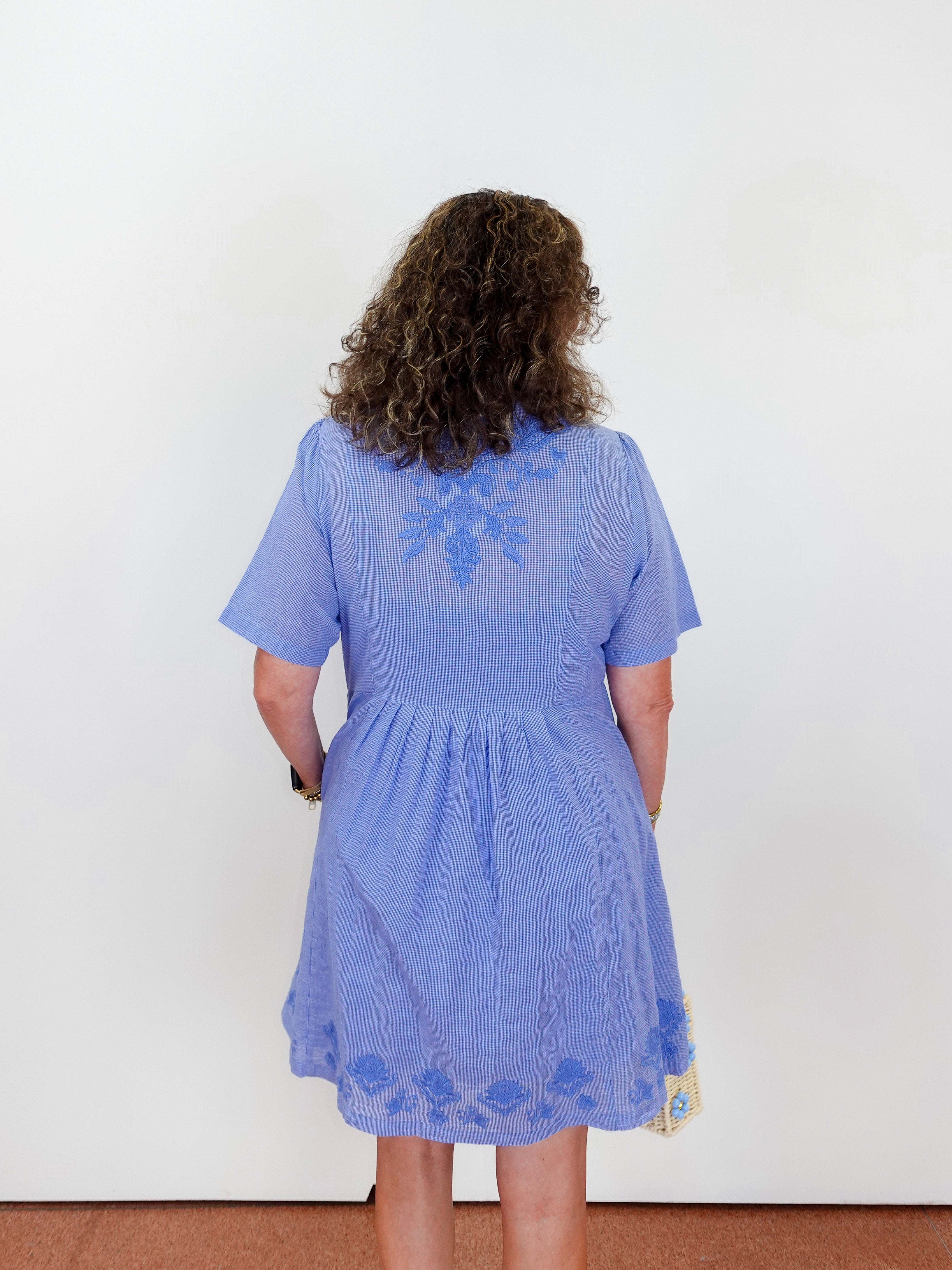 Person wearing a blue dress with lace details on a white background