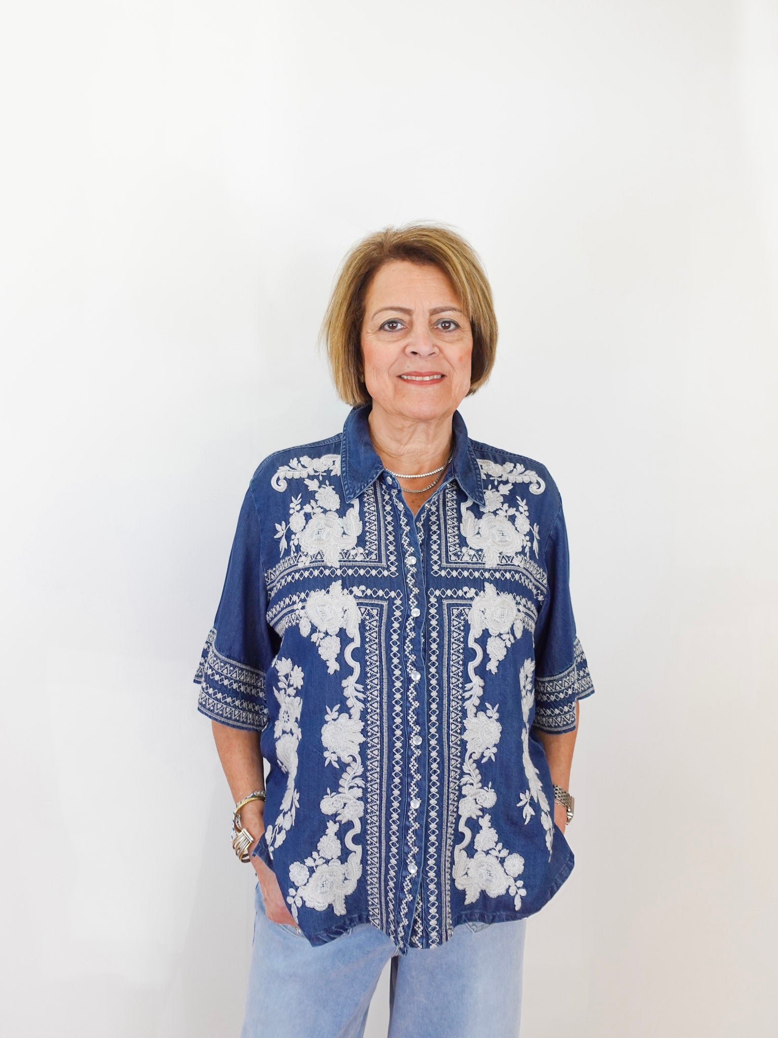 Woman wearing a blue patterned shirt against a white background