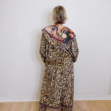 Person wearing a leopard print outfit with a colorful top against a white wall.