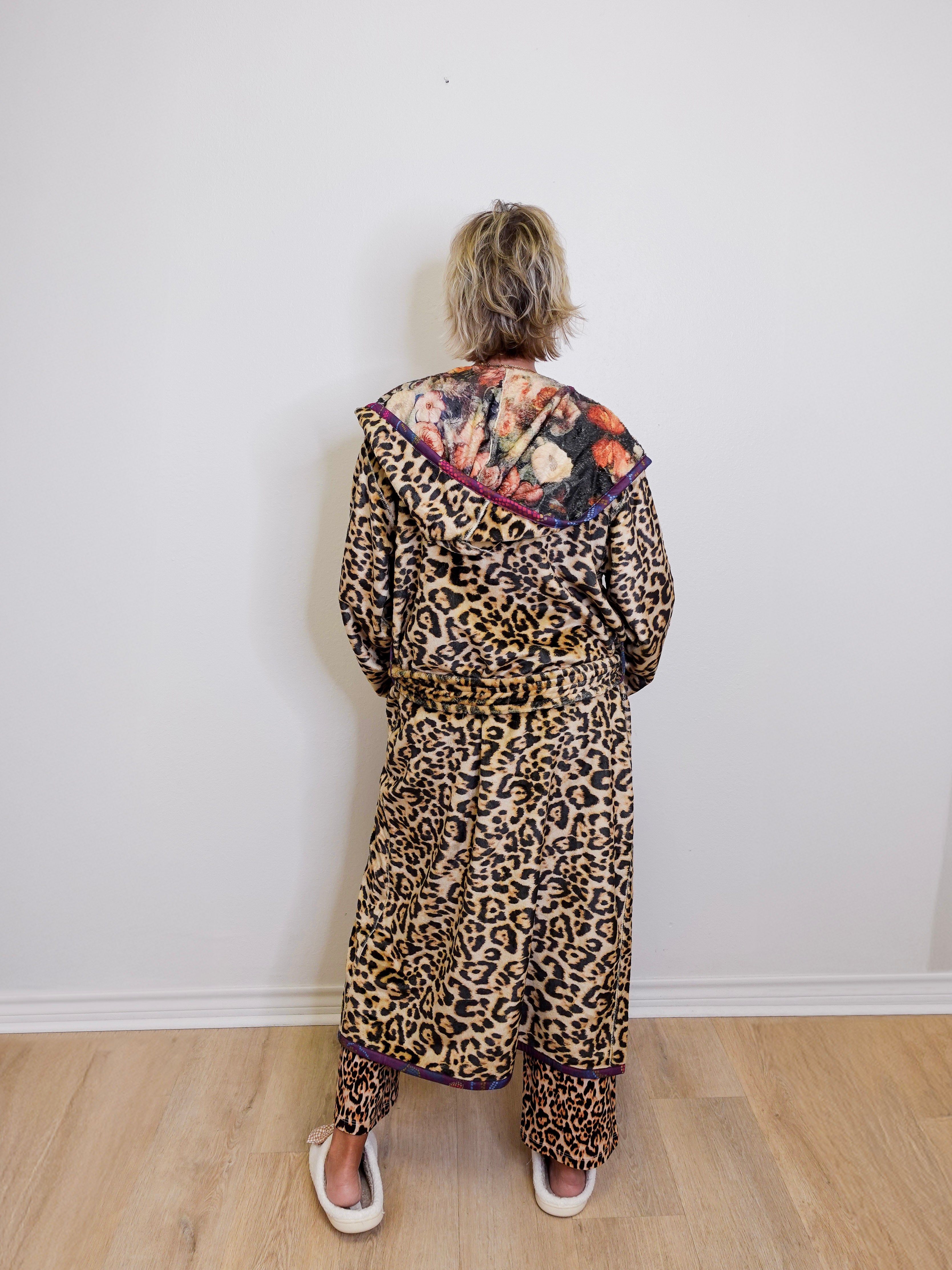Person wearing a leopard print outfit with a colorful top against a white wall.