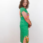 Woman wearing a green dress with floral patterns on a white background