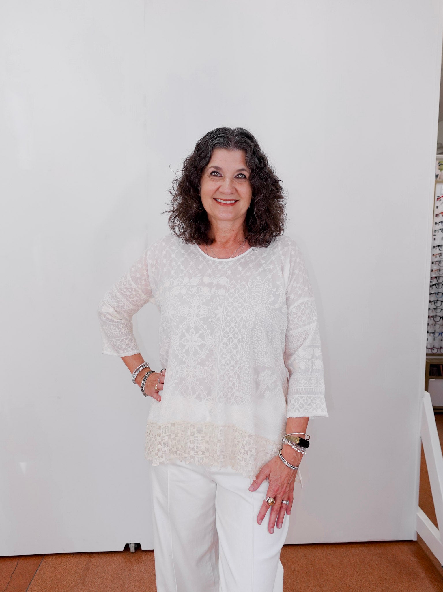 Woman in a white outfit standing against a plain white wall.