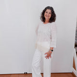 Woman wearing a white outfit standing against a plain white wall.