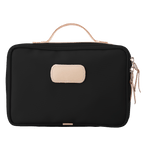 Black toiletry bag with beige handle and patch on a white background