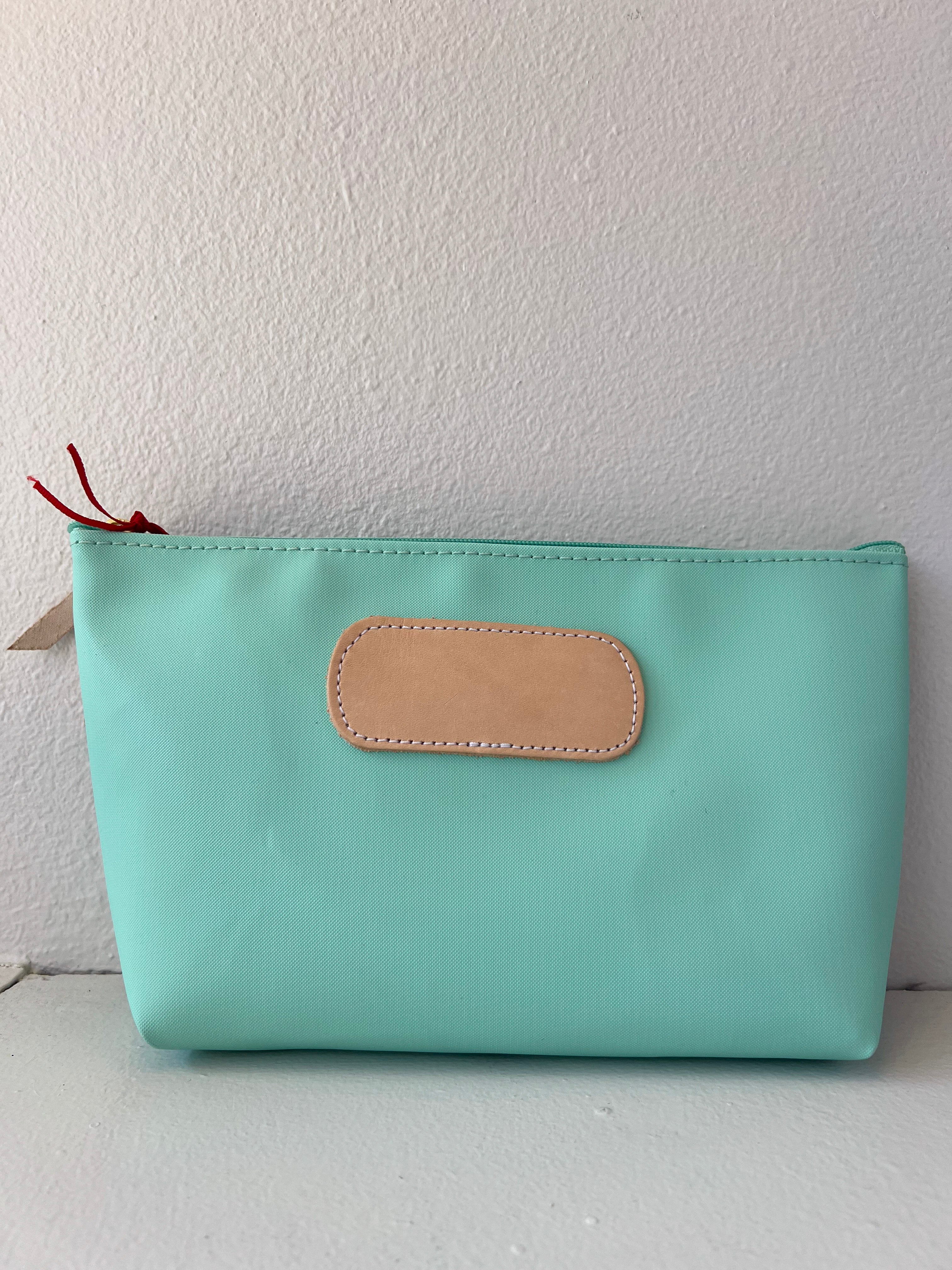 Mint green pouch with a beige patch on a white background