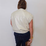 Person wearing a light-colored shirt and dark pants against a plain background